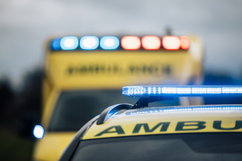 Close-up of blue light flasher on roof of ambulance car of emergency medical service on road. Themes rescue, urgency and health care.